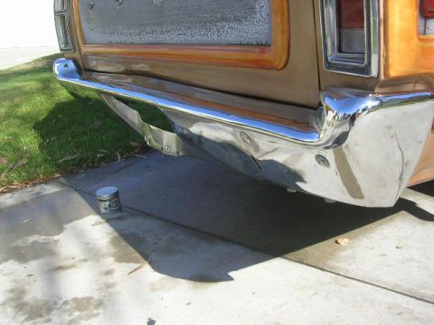 1975 Ford Ranchero - The rear bumper of a pickup truck shows signs of wear and damage, with a can of product nearby.