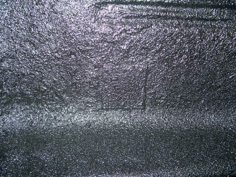 1979 Ford F-150 - A close-up view of a textured black surface, possibly a truck bed liner, with a subtle rectangular imprint visible.