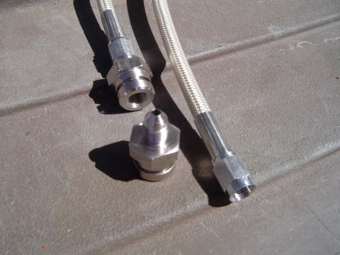 1978 Ford Bronco - Close-up of braided metal hoses and their connecting fittings, laid out on a textured surface.