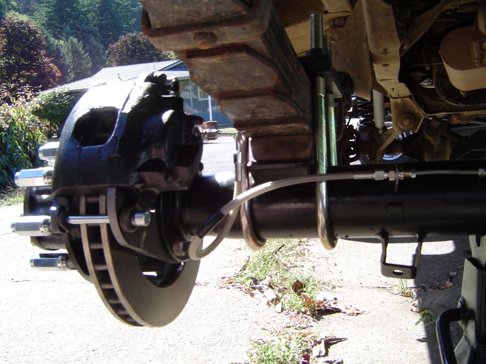 Underside view of a vehicle's solid front axle with disc brake and steering linkage