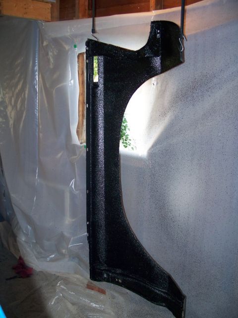 1979 Ford F-150 - A truck fender is suspended and coated with a textured black paint, likely in a garage or workshop setting.