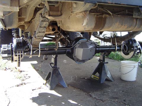 1978 Ford Bronco - Underside view of a vehicle's rear axle assembly, supported by jack stands, with brake components and fuel tank visible.