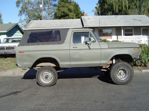 1978 Ford Bronco - Side view of a lifted 1978 Ford Bronco with a soft top, parked on a residential street.