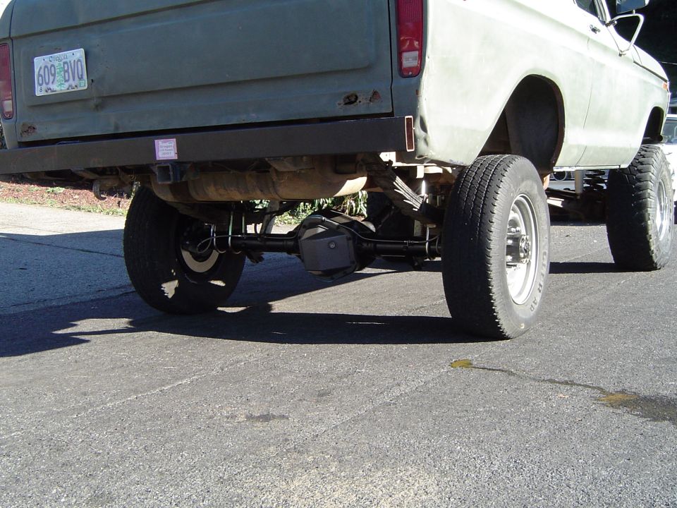 Rear view of a lifted truck showing the axle, leaf springs, and tires. License plate reads 609 BVO