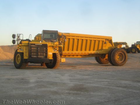 1968 Ford Mustang - This Komatsu articulated dump truck is parked on a dirt lot under a clear sky. Another piece of heavy equipment is visible in the backgroun…