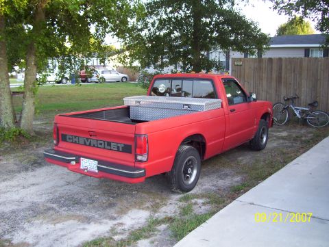 1978 Ford Bronco - A red Chevrolet S-10 pickup truck is parked in a driveway next to a wooden fence and a bicycle.