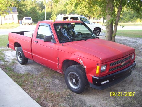 1978 Ford Bronco - A red pickup truck is parked in a driveway with another SUV in the background.