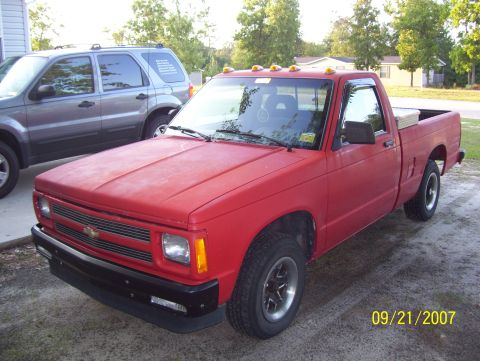 1978 Ford Bronco - Red Chevrolet S10 pickup truck parked next to a silver SUV on a driveway.
