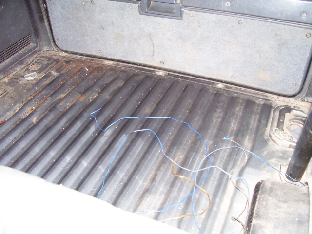 Bare ribbed metal cargo floor of a 4Runner with surface rust and loose blue and brown wires