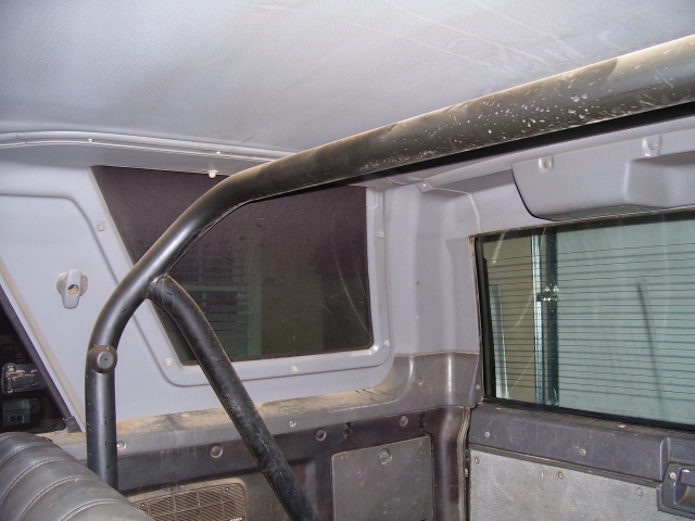 Interior rear cargo area with black roll cage bar along headliner and gray panels