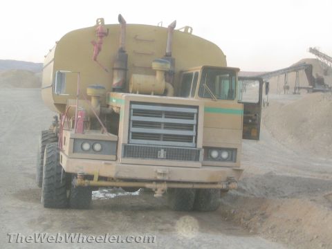 1968 Ford Mustang - A large yellow water truck is parked in a gravel pit with its driver's door open.