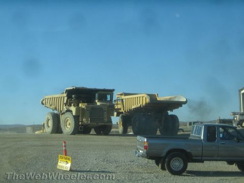 1968 Ford Mustang - A construction site scene with two massive dump trucks and a pickup truck under a clear blue sky.