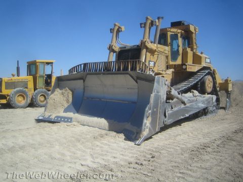 1968 Ford Mustang - Two heavy construction vehicles are parked on a sandy surface under a clear blue sky.