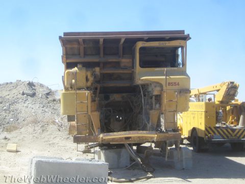 1968 Ford Mustang - A yellow heavy equipment vehicle, possibly a dump truck, is seen from the front with its engine compartment exposed. Another yellow utility…