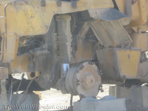 1968 Ford Mustang - The underside of a yellow construction vehicle shows its complex mechanical components and suspension system.