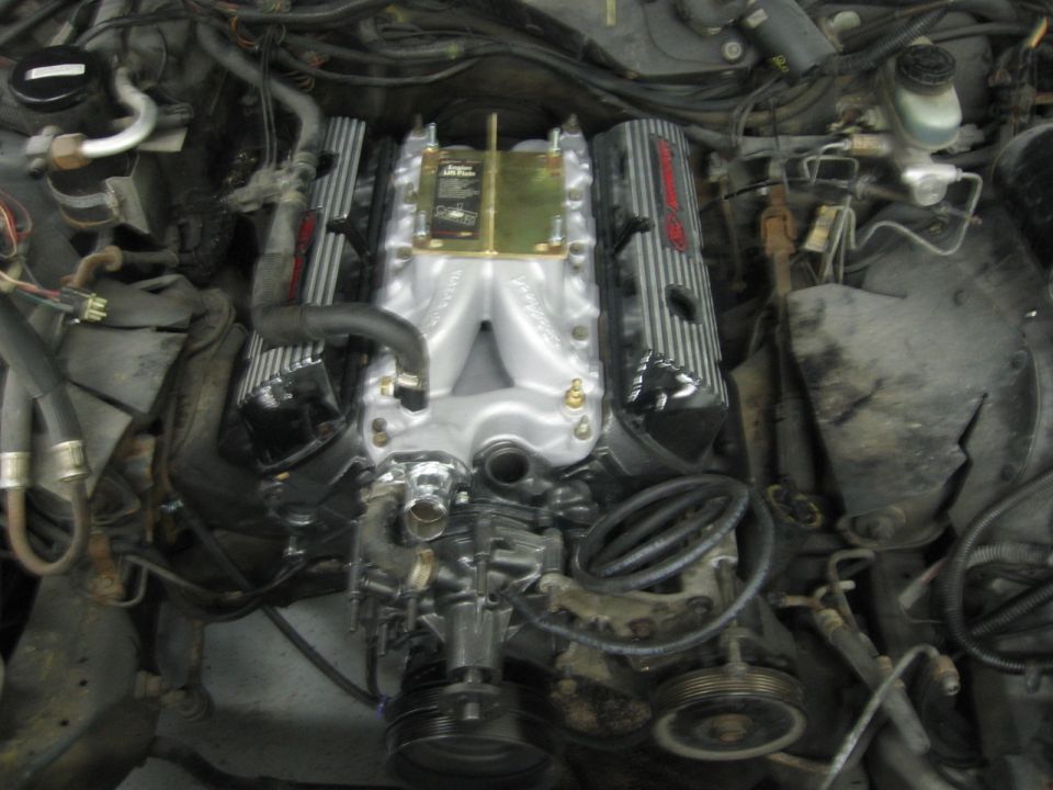 Engine bay showing a V8 engine with polished aluminum intake manifold and chrome valve covers with red lettering