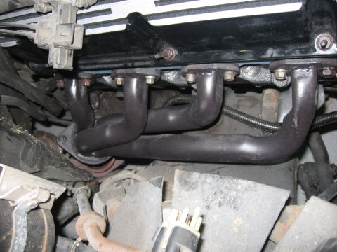 1988 Mercury Grand Marquis - Close-up view of an engine's exhaust manifold and valve cover.