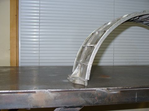 1978 Ford Bronco - A section of a metal wheel rim with visible internal bracing sits on a workbench.