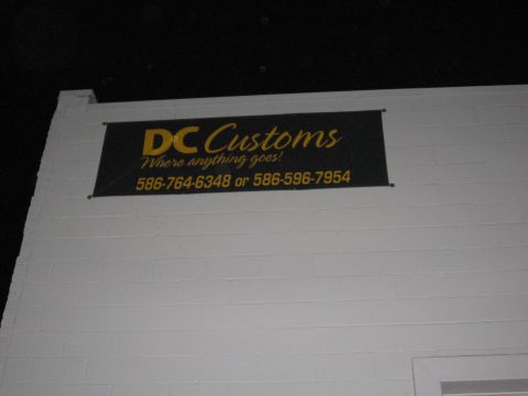 1988 Mercury Grand Marquis - A banner for DC Customs hangs on a white brick wall.