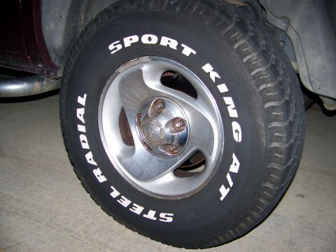 2001 Dodge 1500 - A close-up view of a truck's tire and rim, white lettering and a Dodge emblem on the wheel.