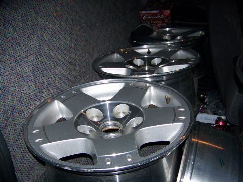 2001 Dodge 1500 - Several alloy rims are stacked and stored inside a vehicle's cargo area.