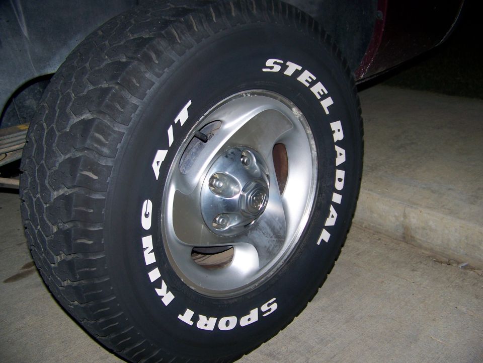 Tire with white lettering 'Steel Radial' and 'Sport King A/T' on a silver 5-lug rim