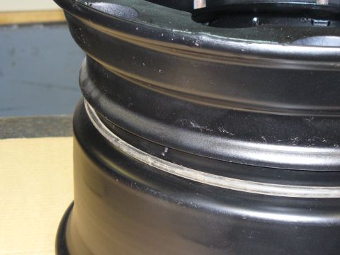 1978 Ford Bronco - Close-up of a black aftermarket wheel rim, showing wear and tear on its surface.