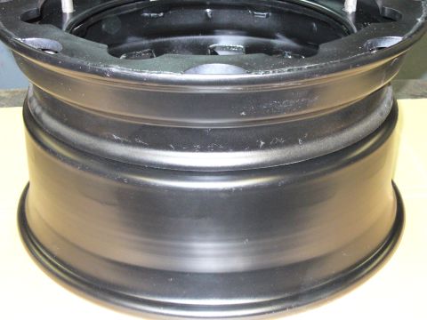 1978 Ford Bronco - Close-up of a black steel wheel rim, showing its construction and mounting points.