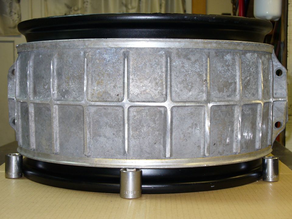 Aluminum wheel rim with black tire, supported by socket wrenches