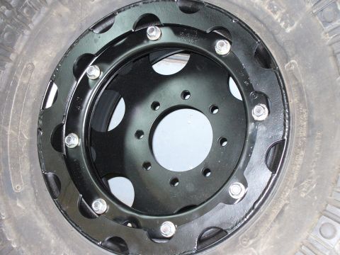 1978 Ford Bronco - Close-up of a black beadlock wheel and tire assembly, the Supermotors.net logo in the lower right corner.