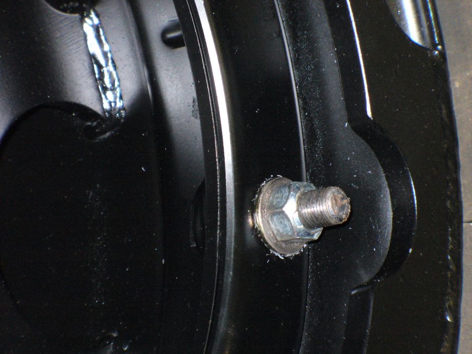 Close-up of a bolt with a washer on black painted metal, possibly part of a vehicle frame