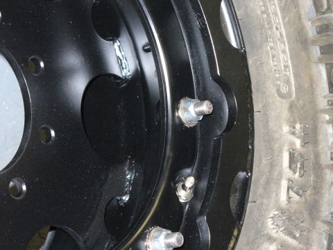 1978 Ford Bronco - A close-up view of a black steel wheel and tire, showing lug nuts and tire tread detail.