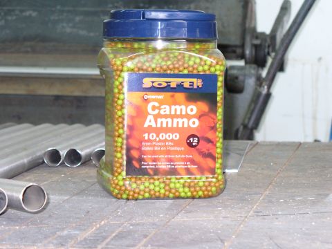 1978 Ford Bronco - A container of camouflage BBs sits on a workbench next to some metal pipes.