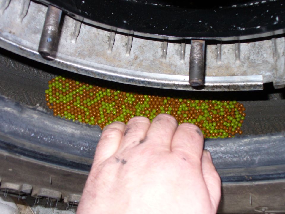 Hand adding balancing beads to a tire