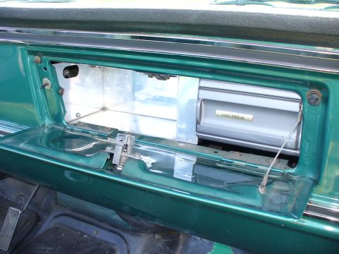 1978 Ford Bronco - Interior view of a green vehicle showing an open glove box with a Premier cassette tape holder.