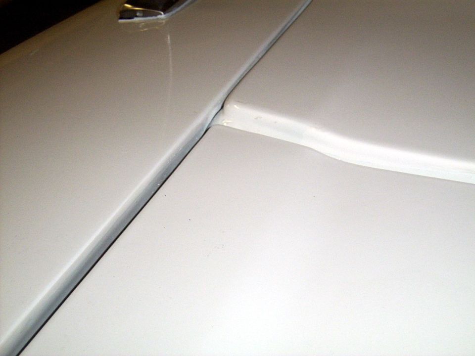 White car hood seam with visible gap and trim piece