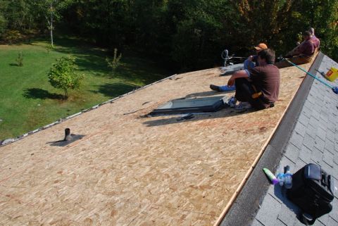 1996 Ford Bronco - Workers are taking a break on a roof that is undergoing repairs, with new plywood sheeting laid down.