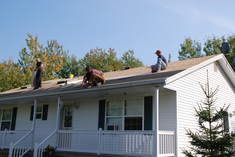 three guys working on a house roof on a clear day