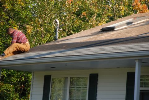 1996 Ford Bronco - A person works on repairing a house roof under a clear sky with autumn foliage in the background.