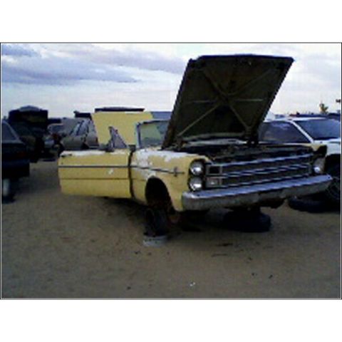 1973 Ford Ranchero - Junkyard scene with a yellow 1965 Ford F-series pickup truck, hood up, and other vehicles in the background.