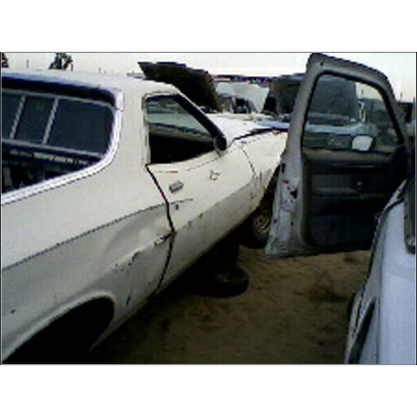 1973 Ford Ranchero with door open, dented fender, in a junkyard