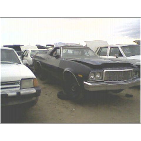 1973 Ford Ranchero - A dark blue Ford Ranchero sits in a junkyard with other vehicles.