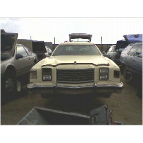 1973 Ford Ranchero - A beige sedan, possibly from the 1970s, is parked in a yard with other vehicles, a light bar on its roof.