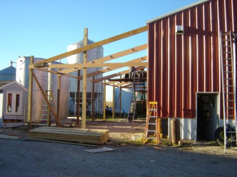 1992 Ford Bronco - A construction site shows a building with a new roof frame being added, alongside silos and lumber.