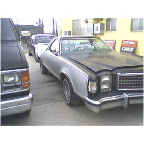 1973 Ford Ranchero - A silver and black pickup truck is parked next to another vehicle, with '77 FORD written on its windshield.
