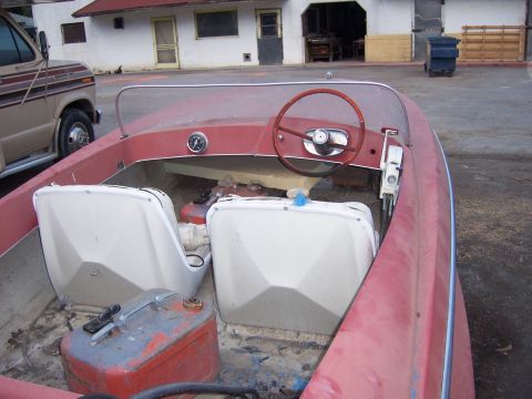 1991 Ford Bronco - The interior of a red boat shows two white seats, a steering wheel, and a portable gas can.