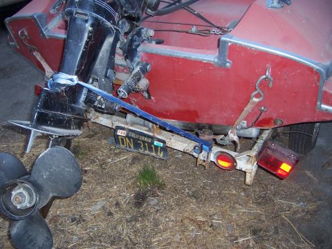 1991 Ford Bronco - A red boat is secured to a trailer with a blue strap, showing its outboard motor and propeller.