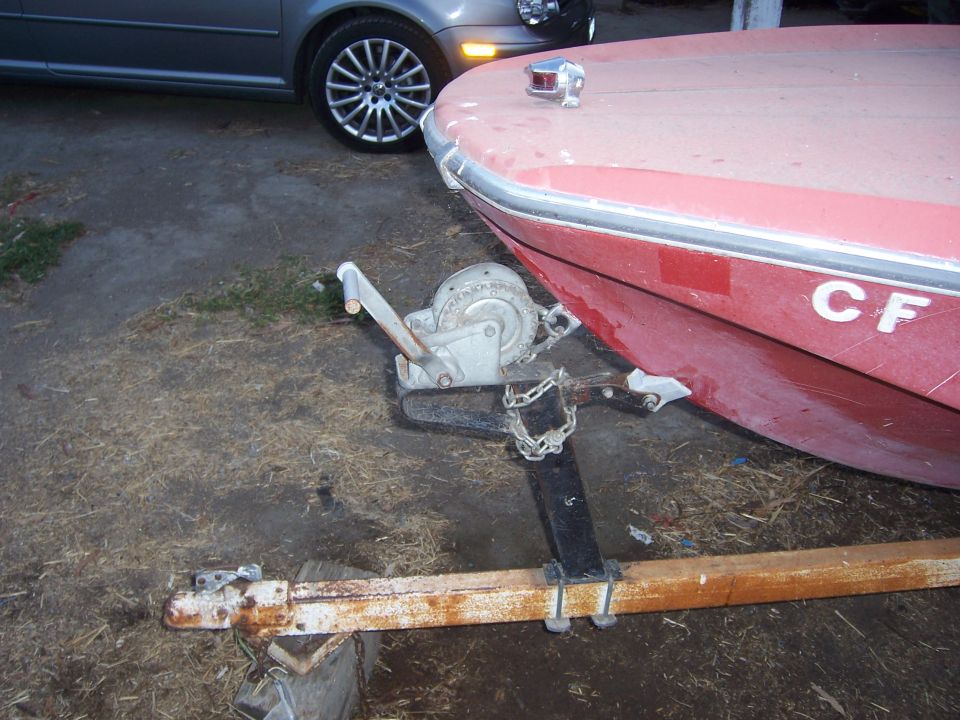 Boat on trailer with winch, car parked nearby