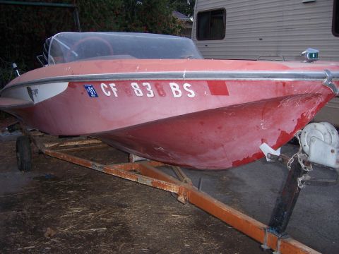1991 Ford Bronco - A red boat with white trim sits on a rusty trailer.