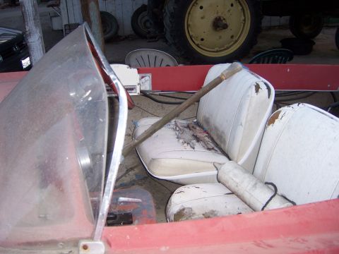 1991 Ford Bronco - Interior of a red boat with worn white seats and a wooden pole across them.